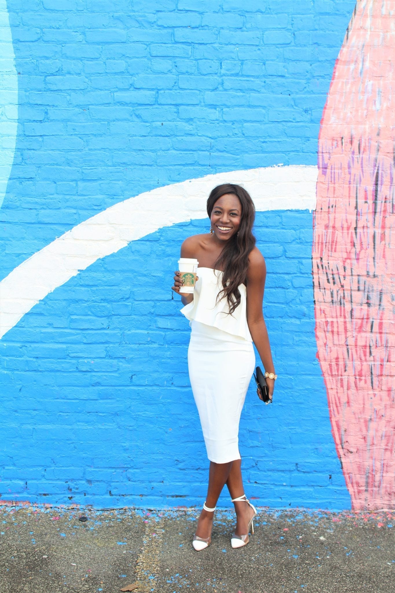 Tomi Obebe is wearing a white Missguided dress and a black Kate Spade wallet