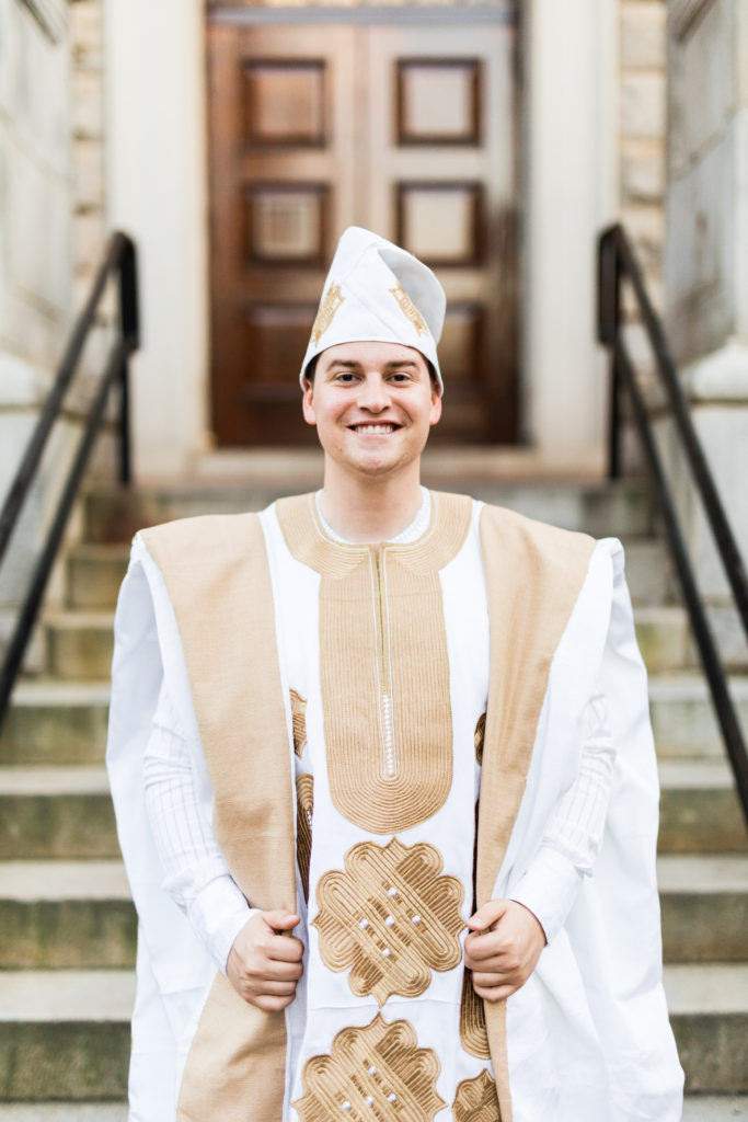White American man in a white and gold agbada and hat for a Nigerian engagement ceremony in Atlanta.
