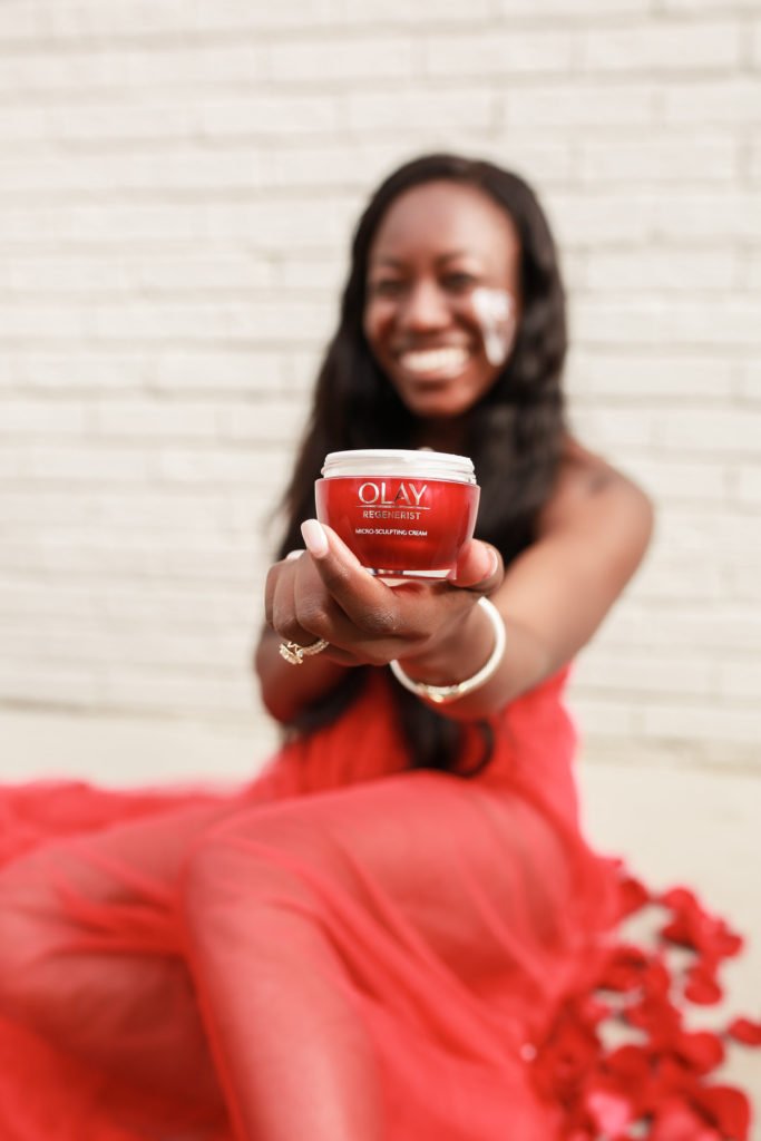 Charlotte Blogger Tomi Obebe poses with Olay red jars for their regenerist whip moisturizers
