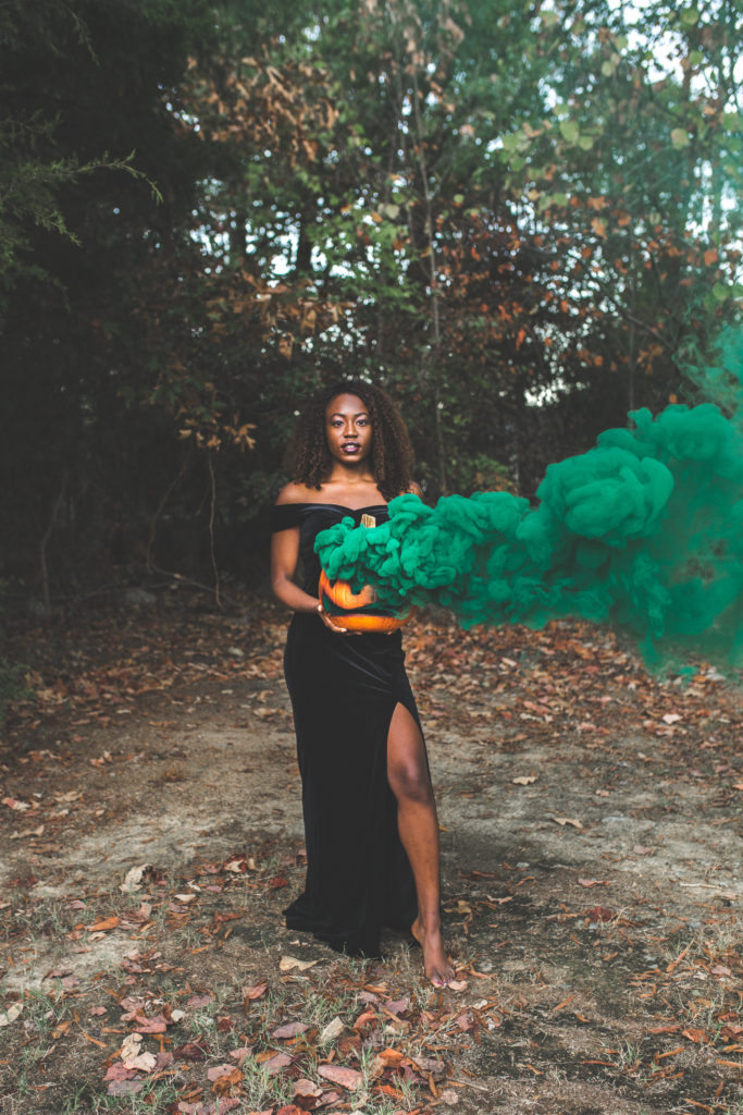 Black woman holding pumpkin with green smoke | Halloween photoshoot