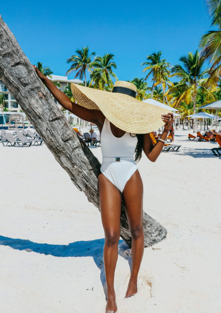 woman wearing white bathing suit and oversize beach hat