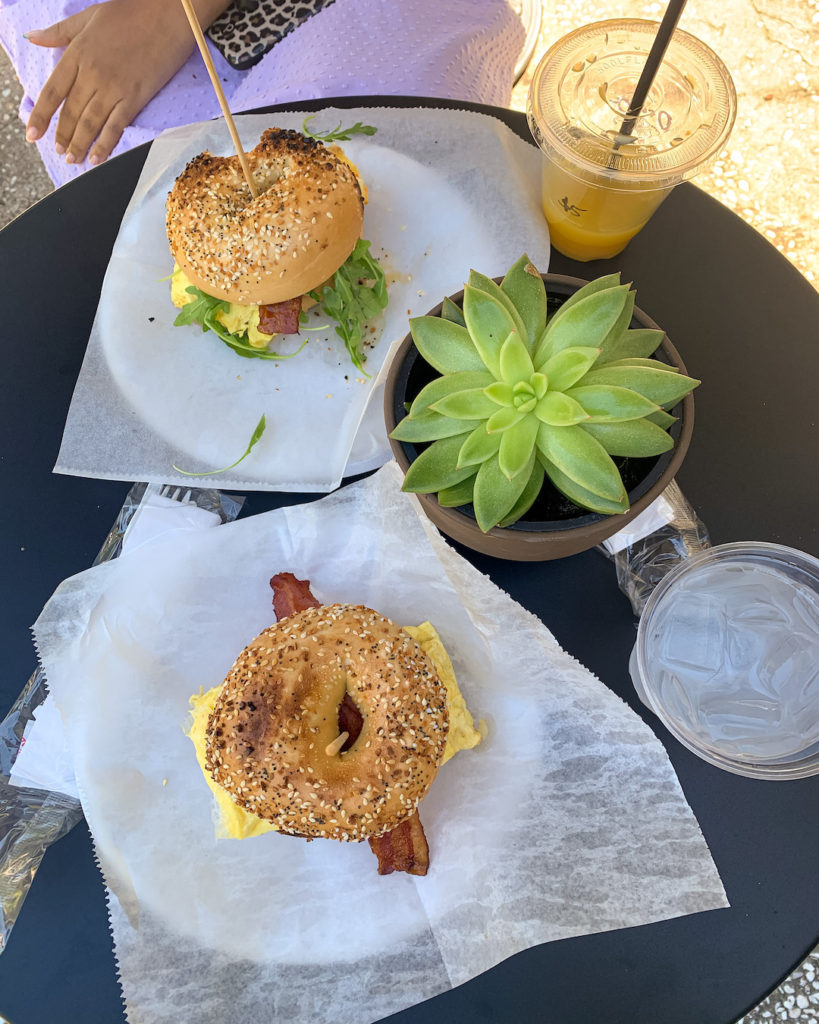 two bagels on a table with plant and drinks for Charleston Trip Recap
