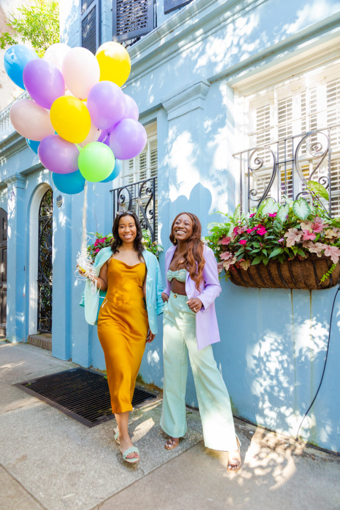 two women wearing pastel clothes and the other woman holding balloon