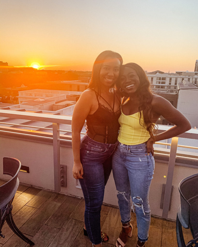 two women in the roof deck with sunset on the background