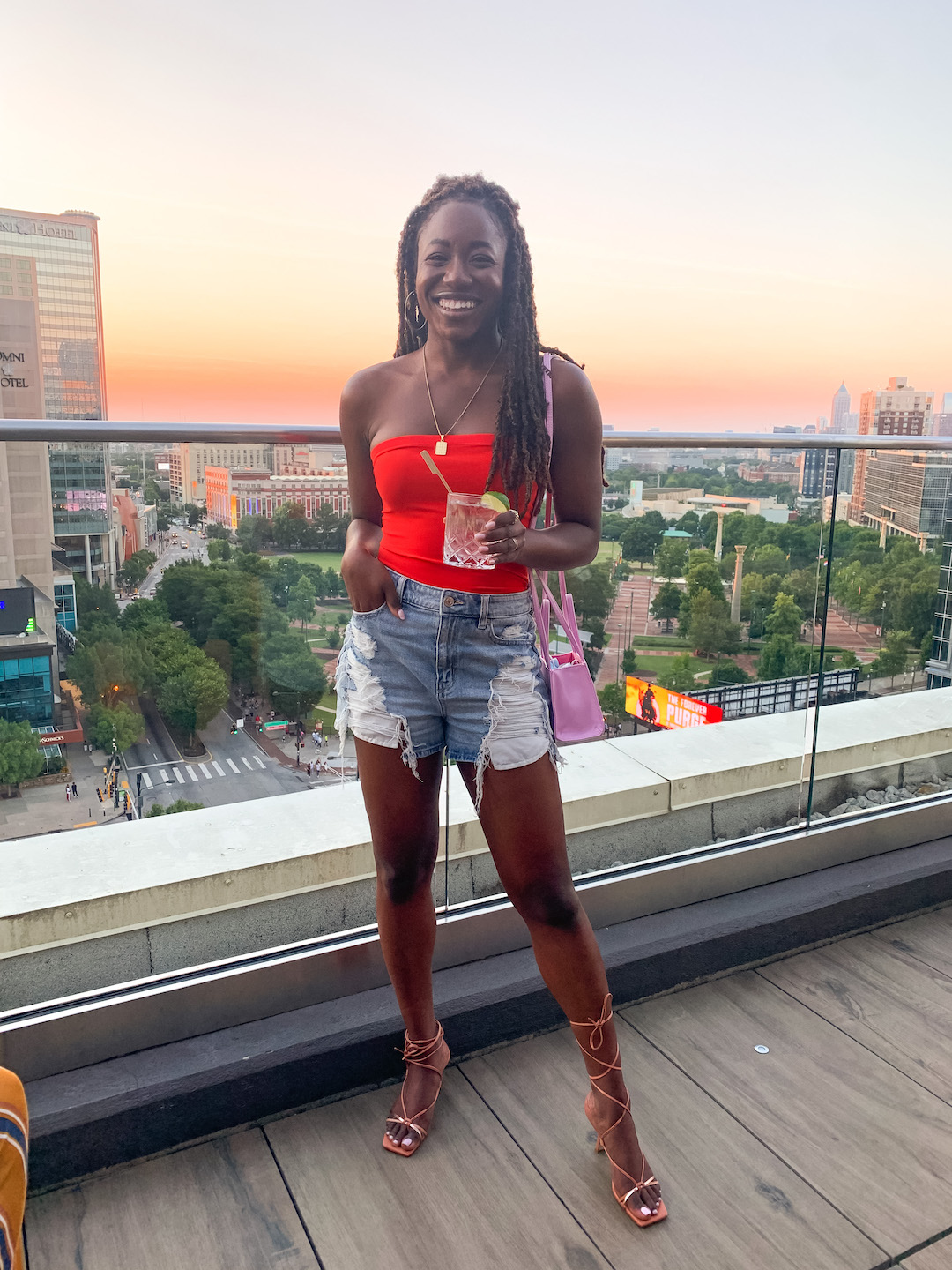 woman standing at the balcony and holding a drink for ATL Blogger Weekend Recap
