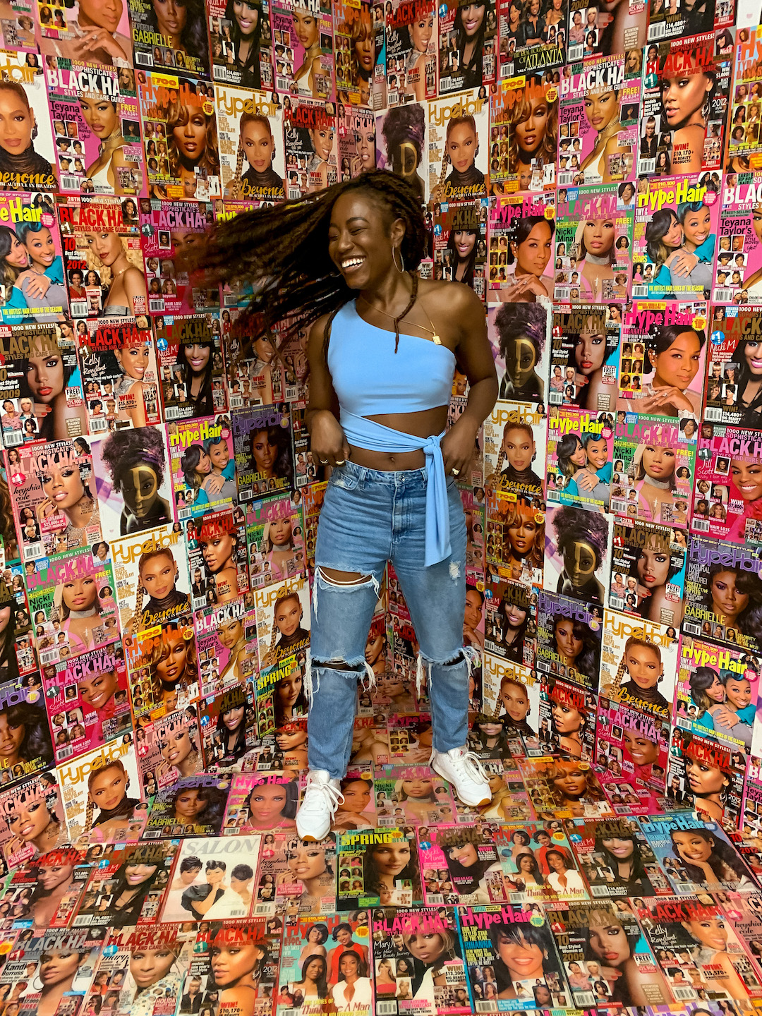 woman whipping her hair with magazine covers in the background 