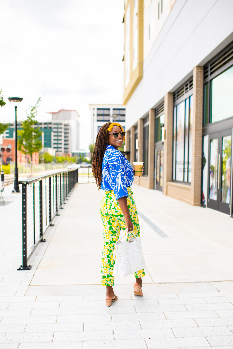 woman walking on the streets and wearing vibrant blue top and yellow and green pants 