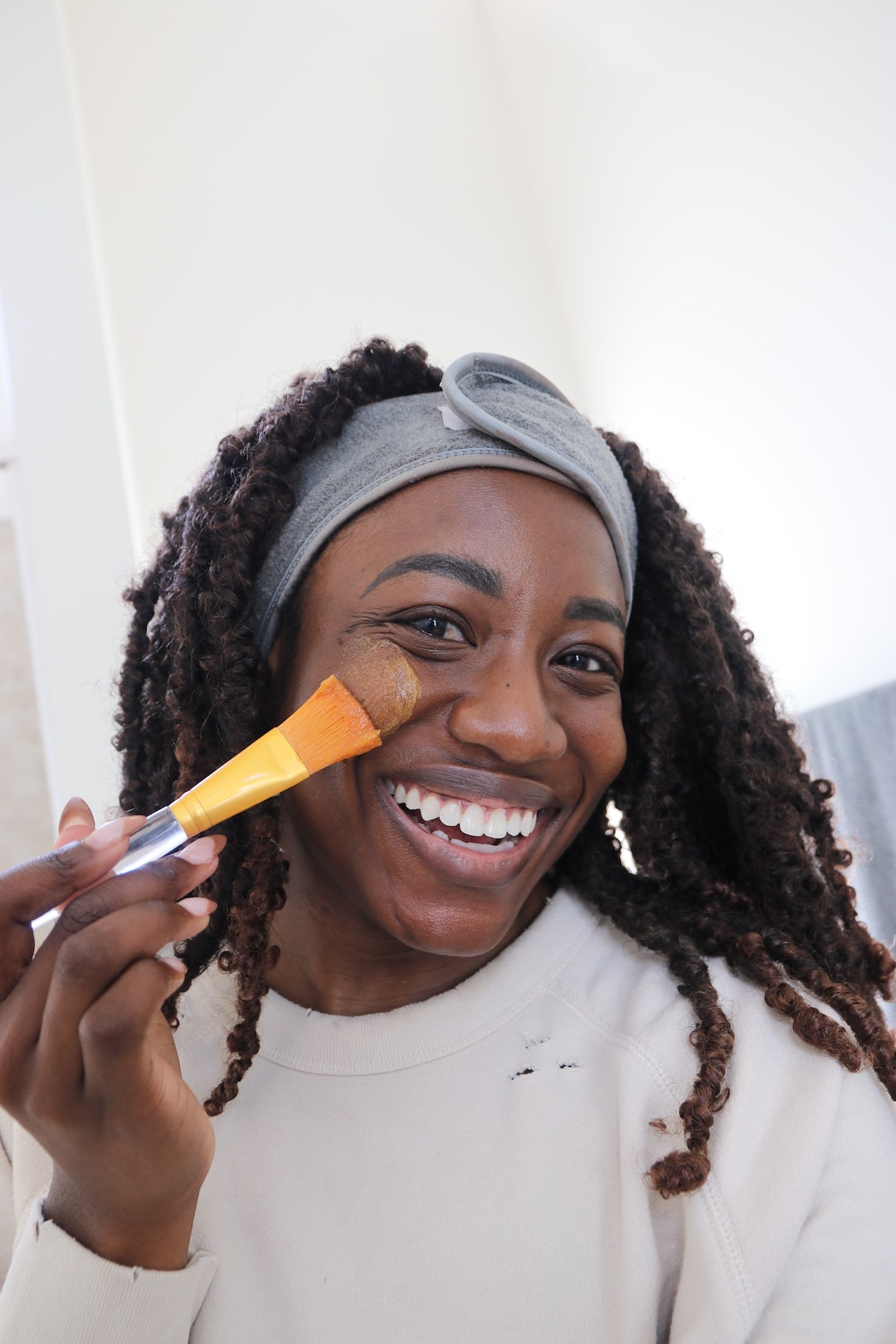 woman applying pumpkin enzyme mask from QVC fall self care items with a brush 
