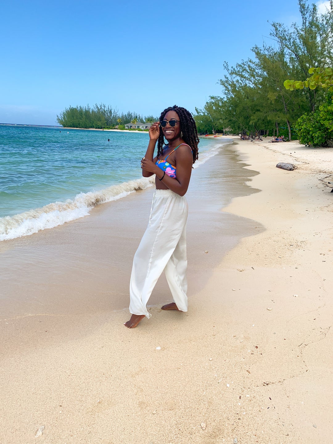 woman sharing what to pack for jamaica wearing swimwear and beach pants