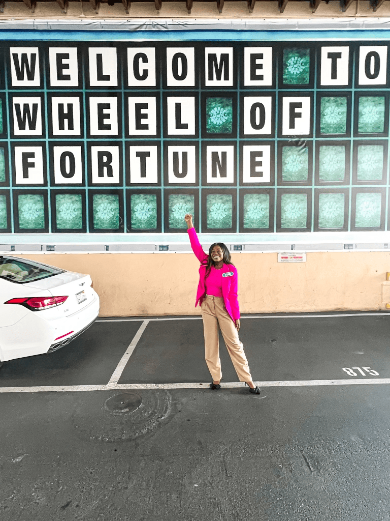 goodtomicha standing in front of the wheel of fortune sign