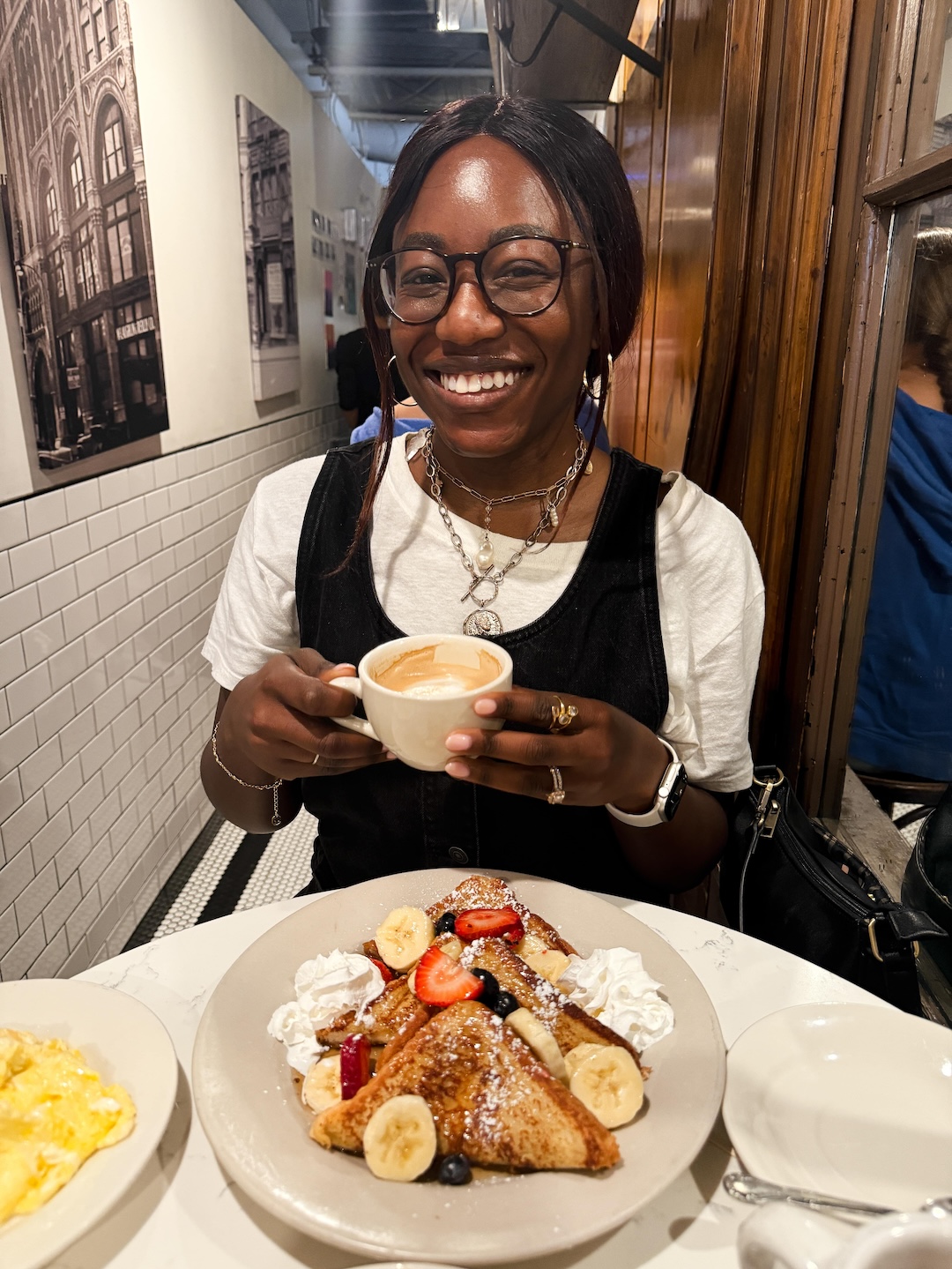 Brunch spread at Café Bonjour in boston with french toast, omelets, and lattes on a marble table with travel influencer, tomi obebe | goodtomicha.com